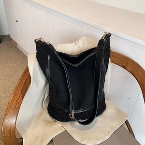 Contrast material black bucket bag with sherpa texture and gold hardware on a wooden chair