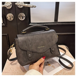 Detail of vintage grey leather handbag with fashion logo and gold metal buckle accents
