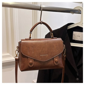 Detailed close-up of brown vintage leather handbag texture and golden brand lettering