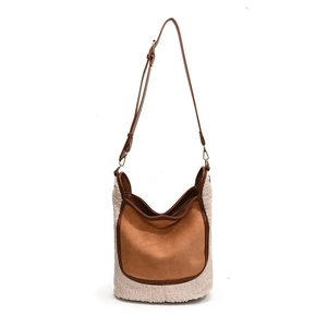 Contrast color bucket bag with fuzzy shearling and brown suede textures in a modern style