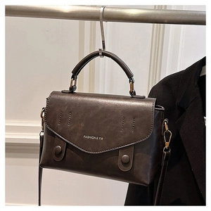 Detail view of the vintage dark brown leather crossbody bag with FASHION & YM lettering