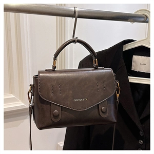 Detailed view of the dark brown retro leather handbag with vintage stitching and gold hardware