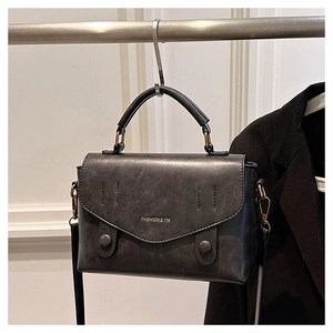 Detail of matte black PU leather handbag with flap cover and fashion brand embossing