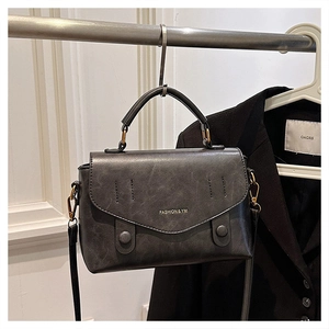 Detail of vintage dark gray leather handbag featuring flap closure and adjustable strap