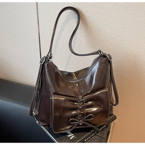 Detail der dunkelbraunen Leder-Handtasche mit großer Schleifenfalte und feinem Riemen