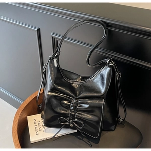 Detail einer glänzenden schwarzen Tote Bag mit dekorativer Falten-Schleife und Lederriemen
