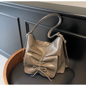 Detailansicht der großen Vordertasche mit Schleifendekoration an glänzender beige Shopper