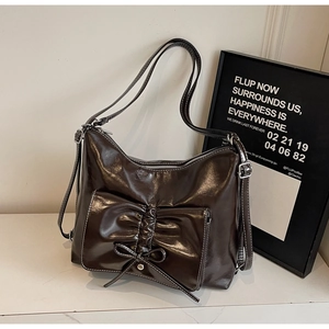 Detail der dunkelbraunen glänzenden PU-Schultertasche mit Schleife und Kontrastnähten