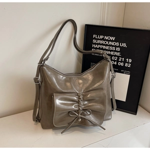 Detail der grauen Schleifen-Schultertasche mit glänzendem Finish und Falten-Außentasche