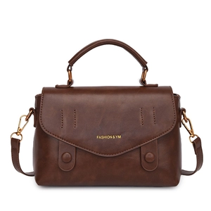 Vintage dark brown crossbody bag with top handle and gold buckle on white background