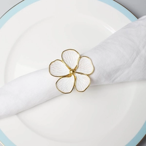 Macro detail of enamel flower napkin ring with gold edges on a white cloth napkin