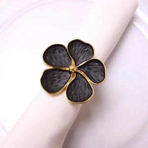 Macro detail of black floral napkin ring with gold trim on white fabric tableware