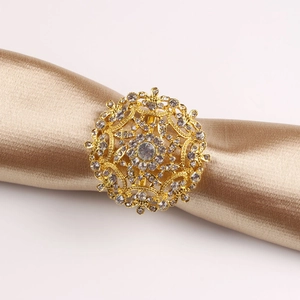 Detalle de un servilletero dorado floral con diamantes de imitación y diseño calado
