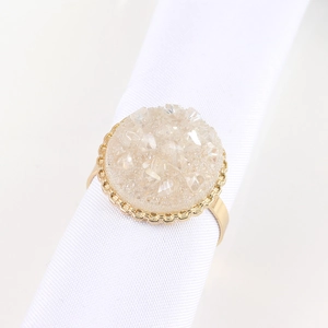 Détail d'un rond de serviette doré orné d'un amas étincelant de druse de cristal
