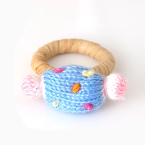 Detail eines handgewebten Serviettenrings mit blauem Strick-Bonbon und bunten Bommeln