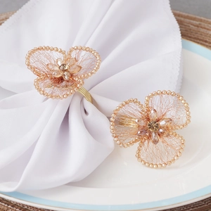 Floral crystal napkin rings with gold bead trim on white linens for wedding decor