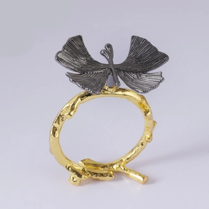 Detail of creative gold branch napkin ring with dark grey ginkgo leaf design