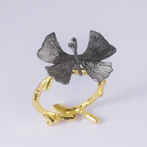 Detail of butterfly napkin ring featuring gun-black wings and gold branch-like base