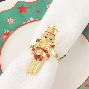 Close-up of golden Nutcracker soldier napkin ring with red glitter on white fabric