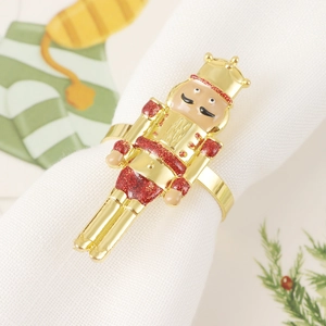 Detail of Nutcracker soldier napkin ring with gold finish and red glitter on white napkin