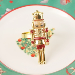 Close-up of golden nutcracker napkin ring with red glitter on a festive dining table