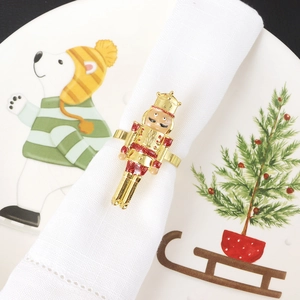 Macro shot of gold nutcracker napkin ring with red glitter on a festive white dinner plate