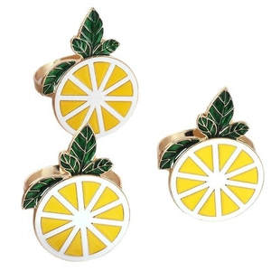 Set of three vibrant yellow enamel lemon slice napkin rings with green leaves on gold bands