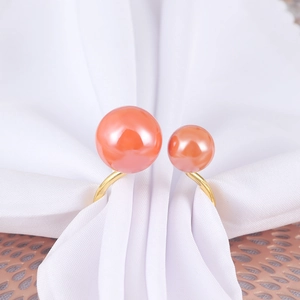 Detailed close-up of coral pink double pearl napkin ring with elegant gold adjustable band