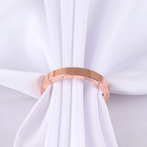 Polished rose gold napkin ring in round metal design on white satin fabric