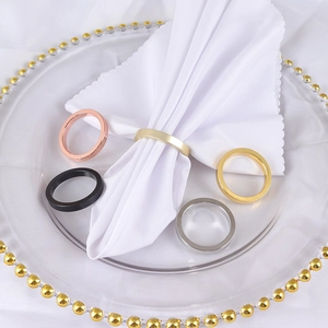 Polished metal napkin rings set in five colors on a glass plate with white napkin