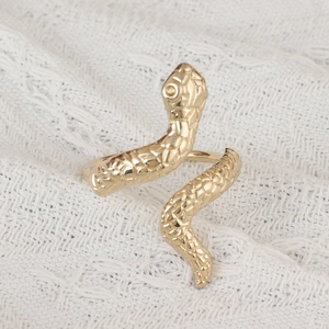 Macro detail of golden snake napkin ring showing textured scales and artistic animal design