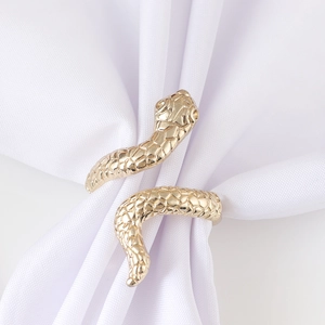Golden snake napkin ring with detailed scale texture on white fabric background
