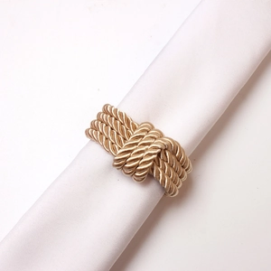 Detail of hand-woven gold silk cord napkin ring on white linen for wedding table decor