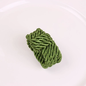 Handwoven grass green knot napkin ring made of lustrous cord on a white ceramic plate