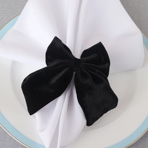 Elegant black velvet bow napkin ring set on a white ceramic plate for table decor