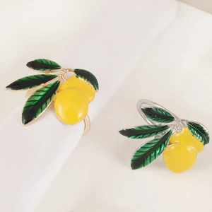 Detailed view of yellow enamel lemon napkin rings with green leaves on white fabric