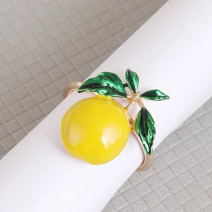 Detail of a yellow lemon enamel napkin ring with green leaves on a gold band