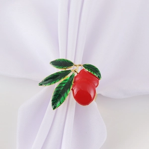 Detail of creative red cherry napkin ring with green leaves on a white linen napkin