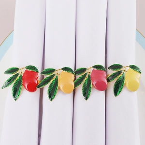 Detailed view of colorful mango napkin rings with gold plating on white napkins
