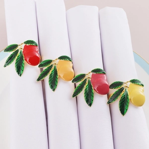 Set of four metal napkin rings with red and yellow mango enamel fruit designs on napkins