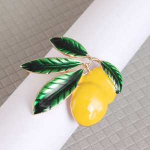 Macro shot of yellow lemon napkin ring with green enamel leaves and golden metal finish