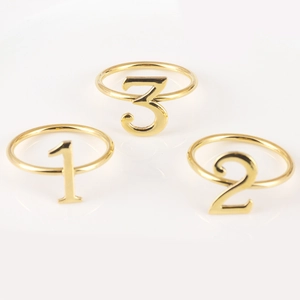 Detailed view of polished gold number 1 2 3 napkin rings for festive table settings