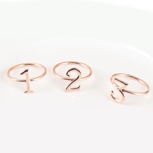 Close-up of rose gold numbered metal napkin rings with digits one two and three