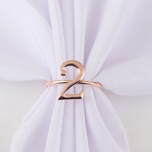Detail of rose gold number 2 napkin ring on white fabric for party table setting decor