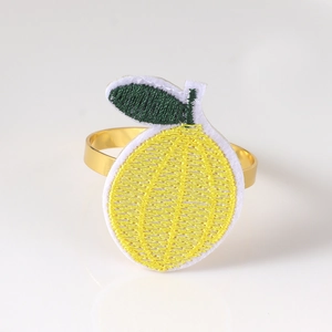 Detail view of handmade lemon embroidery patch on polished golden metal napkin ring