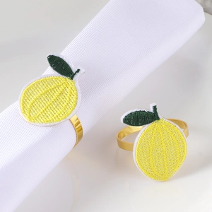 Detail of handmade embroidered lemon motif on a golden metal napkin ring holder