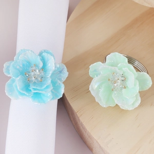 Detail of floral napkin rings in blue and green with a pearlescent resin finish