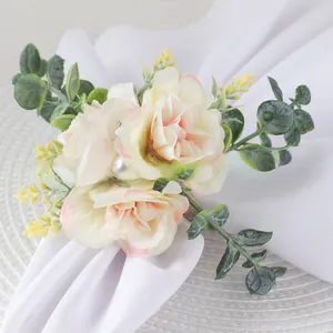 Close-up of rose napkin ring with eucalyptus leaves and pearl detail on white cloth