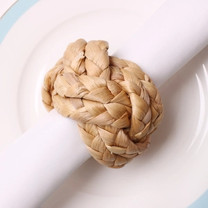 Macro detail of hand-woven corn husk napkin ring with ball knot on white fabric