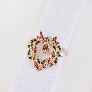 Golden Christmas bell wreath napkin ring with red and green rhinestones on white cloth